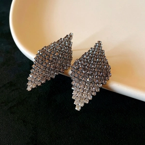 Dettaglio di orecchini vintage a forma di foglia con zirconi su ceramica bianca