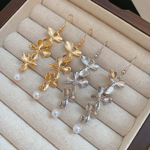 Detail of flower tassel earrings in gold and silver finish with elegant white pearls