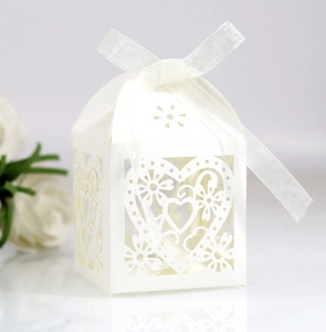 Detailed laser-cut heart pattern on white wedding favor box with a satin ribbon