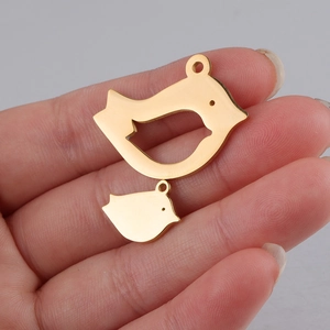Detailed view of polished gold mother and baby bird charms held in a hand