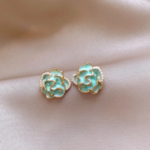 Macro detail of vintage floral stud earrings with blue petals and golden pearl trim