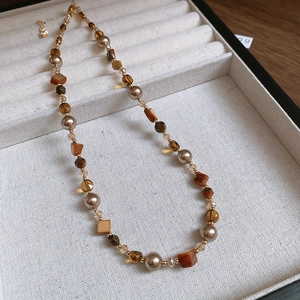 Detailed shot of tiger eye beads and golden heart pendant necklace in a soft velvet box
