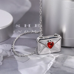 Macro shot of a silver envelope pendant necklace featuring a polished red heart gemstone