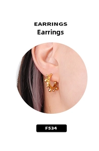 Close-up of golden beaded C-shaped hoop earrings worn on ear for fashion showcase