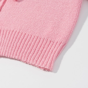 Close-up of pink knitted top showing fine fabric texture and ribbed hem craftsmanship