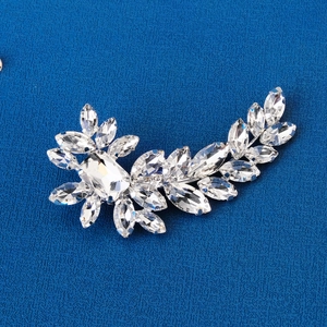 Macro detail of leaf-shaped crystal hair clip with marquise rhinestones on blue fabric