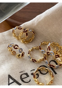 Detail of gold-plated chain rings with blue and red enamel on a linen bag