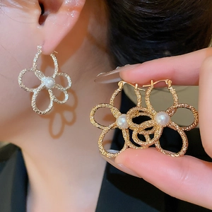 Macro view of textured metal flower earrings with pearls in gold and silver finish
