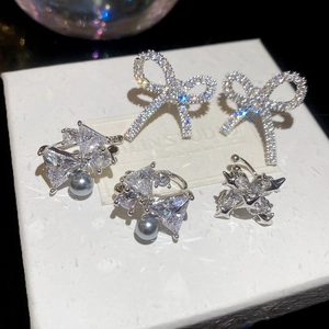 Elegant bow zircon ear clips and pearl earrings set on a white luxury display box