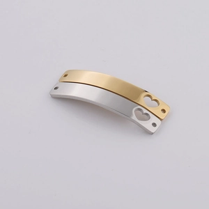 Macro shot of curved rectangular stainless steel bar charms with heart cutouts in gold and silver