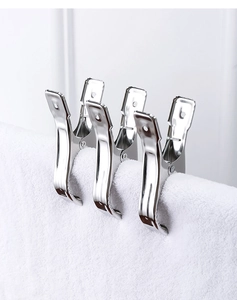 Close-up of three large stainless steel pegs holding a white towel on the edge