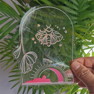 Rainbow suncatcher window film showing iridescent moth and moon details held by hand