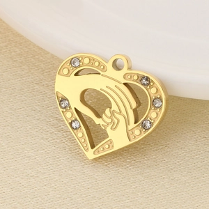 Macro detail of heart-shaped gold mama pendant featuring holding hands and sparkling rhinestones