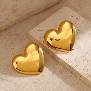 Gros plan de boucles d'oreilles cœur dorées sur pierre naturelle au style moderne