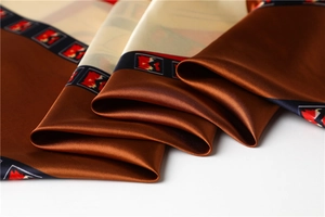 Close-up of smooth brown satin scarf featuring elegant geometric blue and red borders