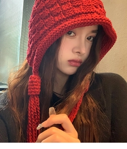 Detail view of handmade red chunky knit beanie with stylish thick braids and long tassels