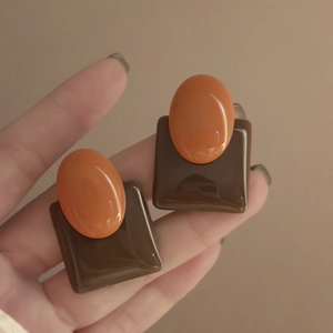 Close-up of geometric resin earrings in vintage brown and orange oval design
