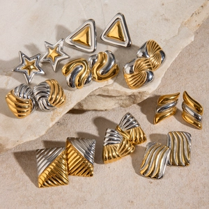 Flat lay of geometric gold and silver two-tone stainless steel earrings on stone