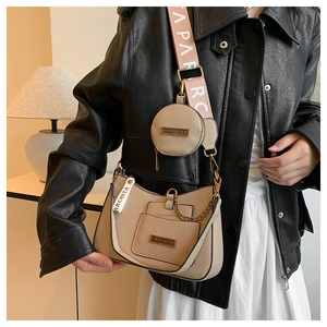 Detail of a chic cream underarm bag with a round coin purse and woven embroidery strap