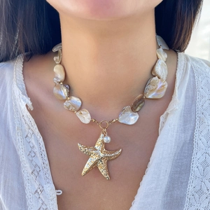 Detail of a natural shell fragment necklace with gold starfish and pearl on a model