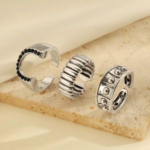 Detail of three vintage silver rings with black stones and textured patterns on silk