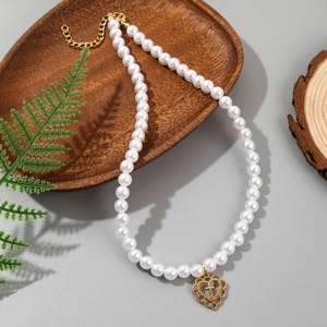 Detail of baroque pearl necklace with golden heart cross pendant on wooden tray