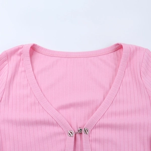 Gros plan du cardigan rose en maille côtelée avec col en V profond et boucle de chaîne en métal