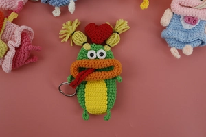 Detail of hand-crocheted monster key cover with funny orange lips and green knit texture