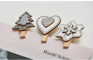 Macro shot of silver glitter wooden clips in snowflake and star shapes on a book
