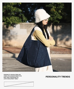 Close-up of a large navy blue nylon tote bag with pleated texture for casual street style