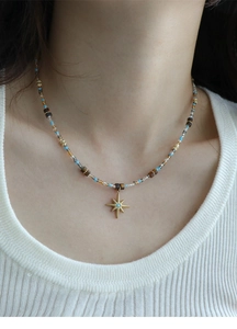 Detail of beaded necklace with gold star pendant and blue stone on model