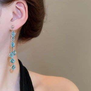 Dettaglio di orecchini a nappa lunghi con perle di vetro blu sfaccettate su modella