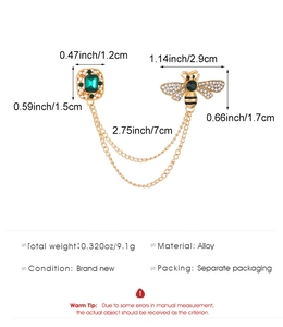 Detailed view of alloy bee brooch set with green gemstone and pearls on golden chains