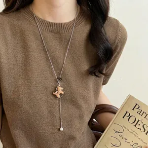 Vintage wooden horse pendant necklace on brown sweater background for a chic winter look