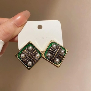 Close-up of vintage geometric square earrings with green enamel and pearl inlay details