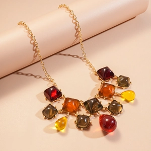 Détail d'un collier bohème en résine avec pendentifs ambrés sur une chaîne dorée