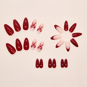 Close-up of almond shaped burgundy cat-eye press-on nails with 3D bow and french design