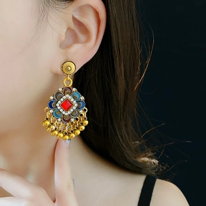 Détail de boucles d'oreilles ethniques vintage avec gemmes rouges et pompons dorés