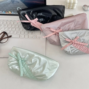 Detailed view of four bow pencil cases in black, pink, silver, and green nylon fabric