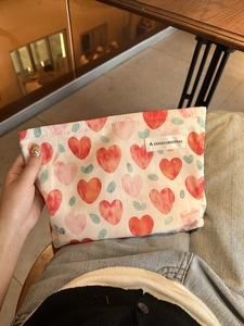 Close-up of heart pattern fabric pouch with A GOGO ORIGINAL woven label on beige cloth