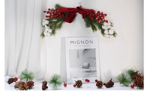 Close-up of Christmas swag with pine needles, red berries, and a velvet bow decoration