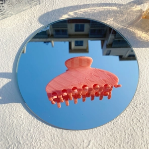 Détail de la pince à cheveux marbre rose sur miroir reflétant le ciel bleu et nuages