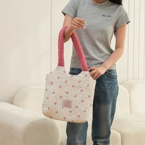 Quilted canvas tote with cherry pattern and pink fleece handles in a home setting