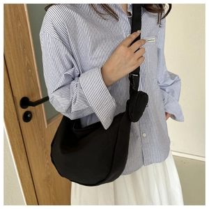 Black nylon half-moon crossbody bag with matching coin purse on a fashion model