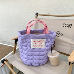 Détail du sac à main violet matelassé à cœurs sur une chaise pliante en extérieur