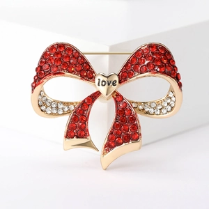 Close-up of red and gold bow brooch with sparkling rhinestones and love heart detail