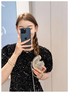 Chic silver conch shell clutch bag with beaded chain shown with a sequined dress