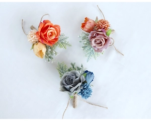 Detailed view of handmade wedding boutonnieres in orange, purple, and blue silk flowers