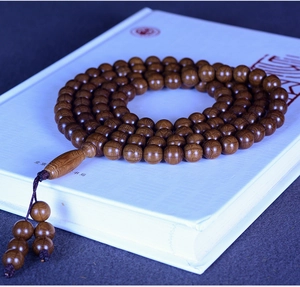 Macro detail of 108 dark chestnut wooden prayer beads with natural wood grain and texture