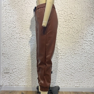 Dettaglio dei jogger in ecopelle marrone scuro con coulisse in vita e polsini elasticizzati